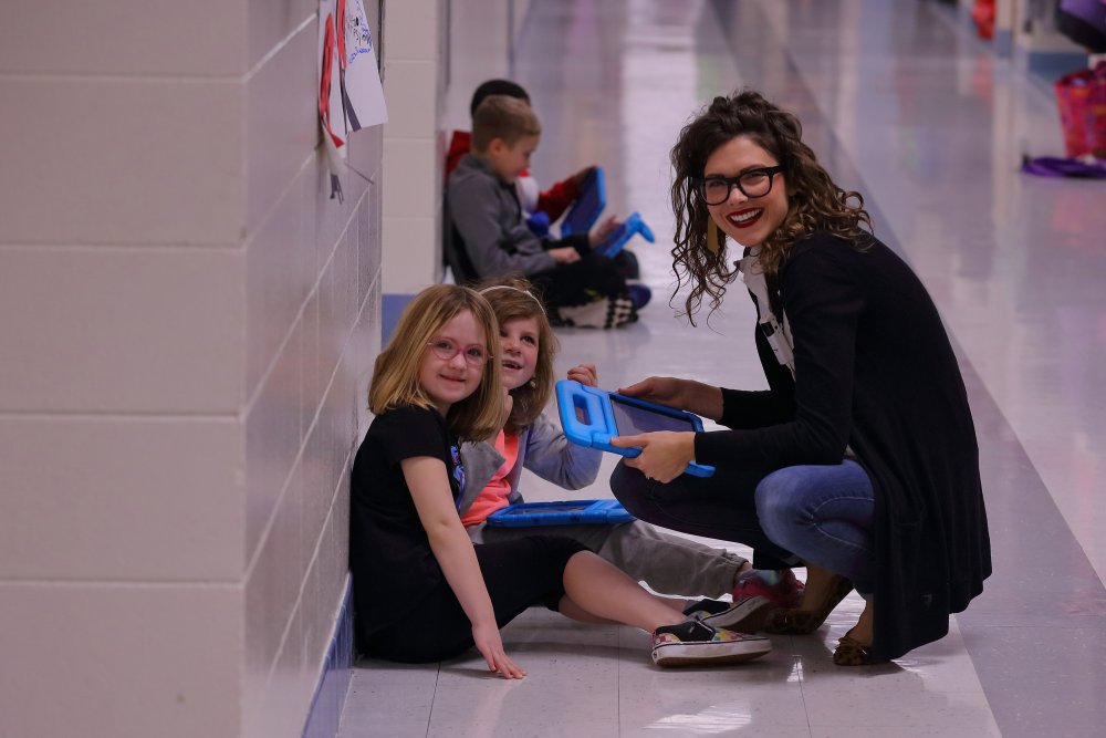 Teacher smiling with students in hallway