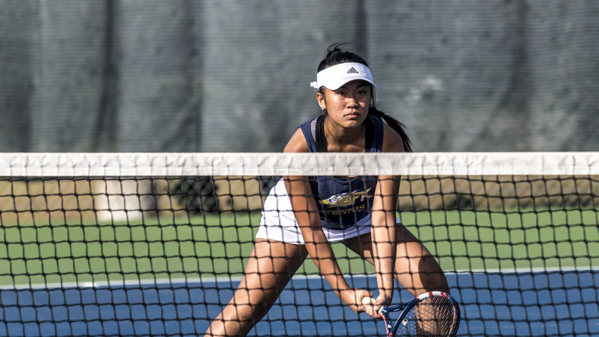 A Kennedy girls tennis player stands ready at the net