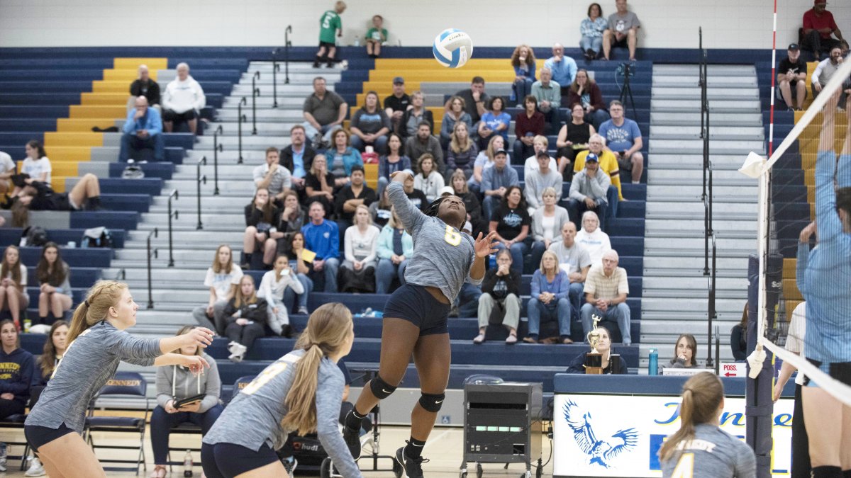 A girls volleyball player jumps in the air for a spike
