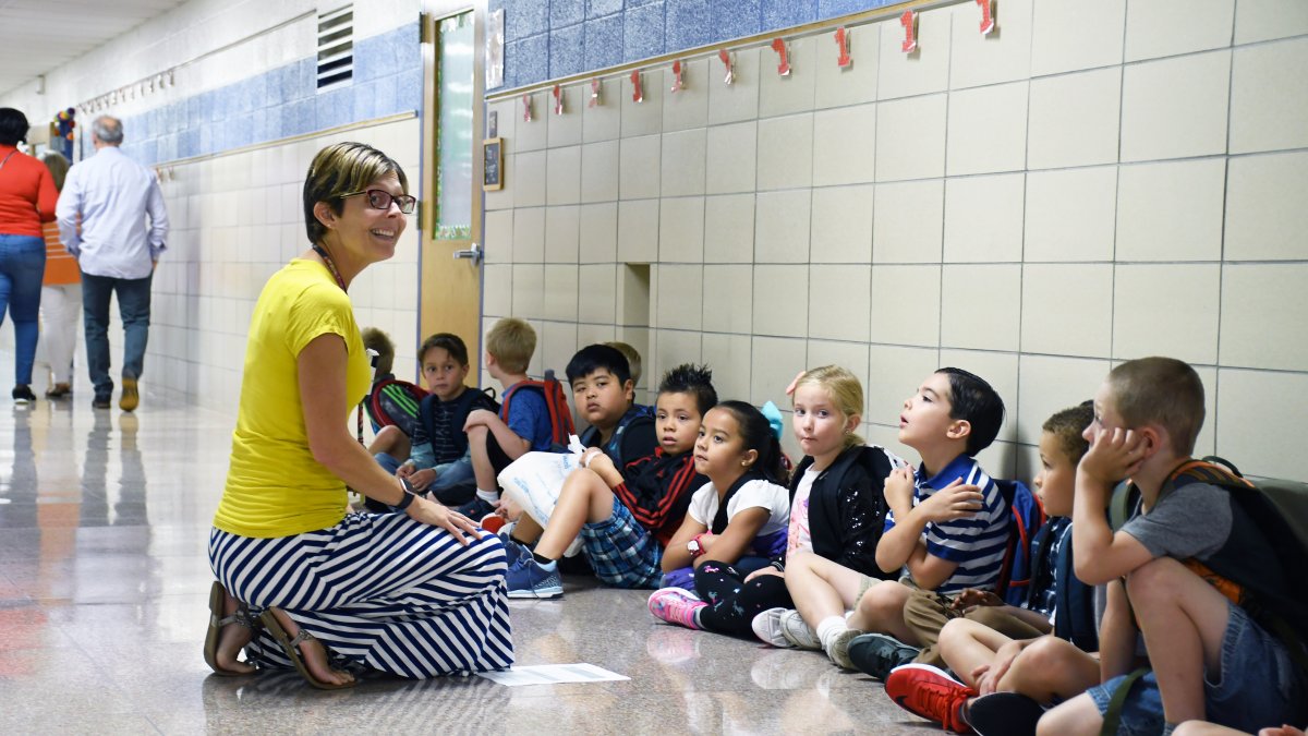 A teacher talks with her students lined up in the hall