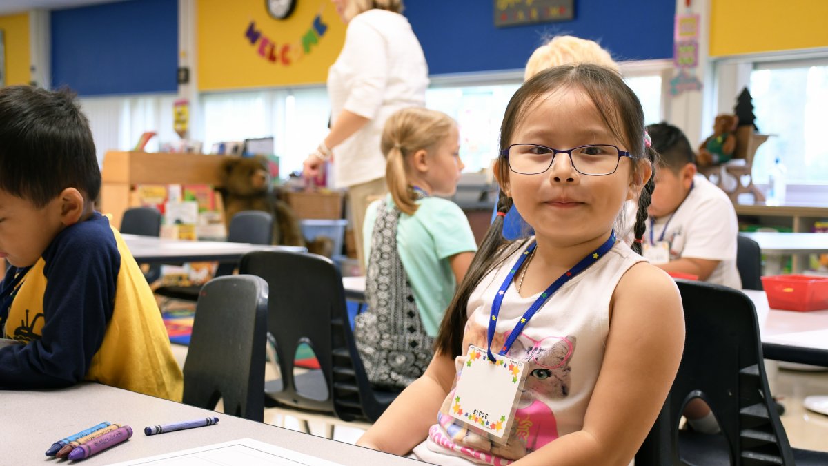 A student smiles at her desk
