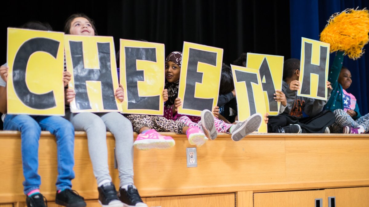 Students hold up signs spelling "CHEETAH"