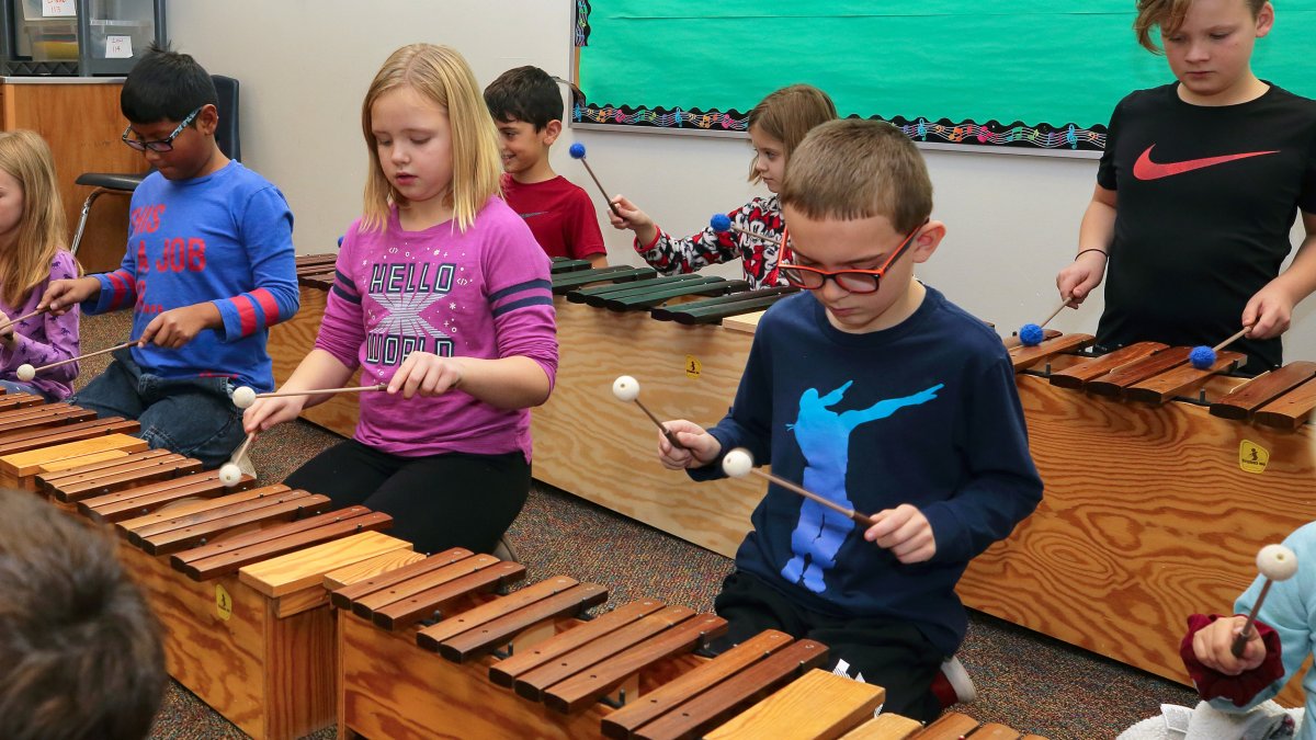 Students play wooden xylophones