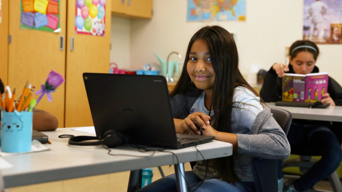 A student smiles while working on a laptop