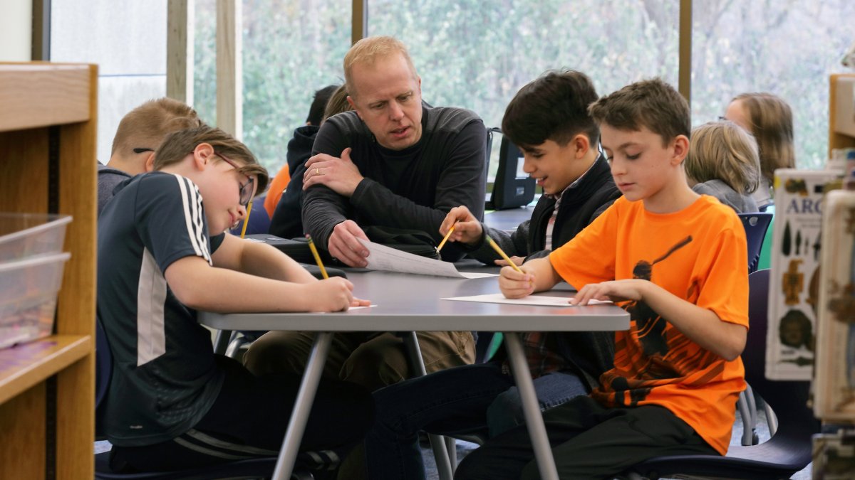 A teacher instructs a group of students at a table