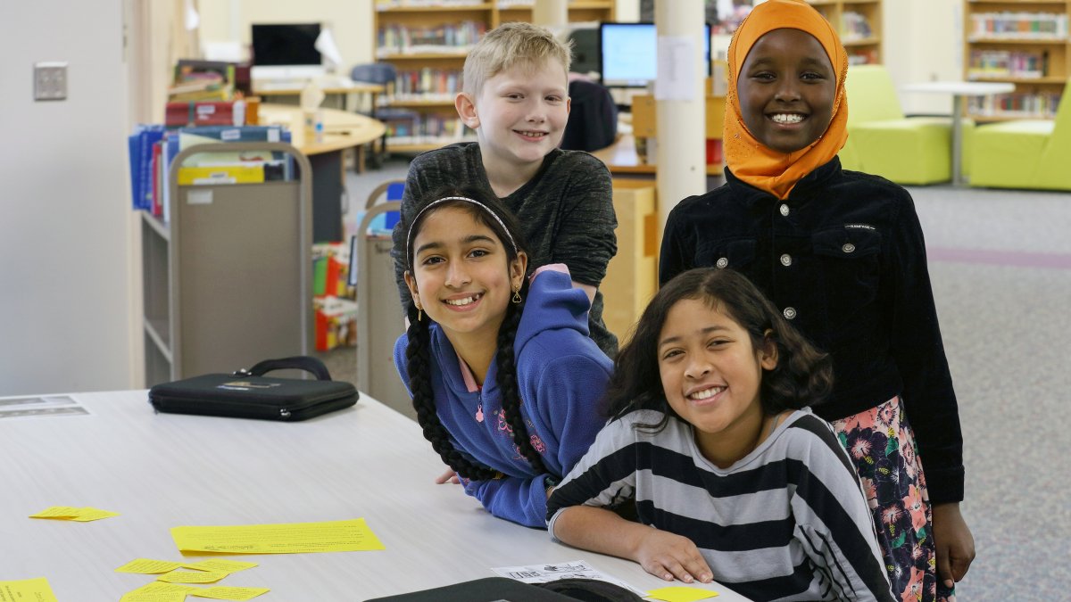 Four students smile in the media center
