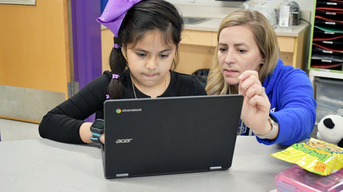 teacher helping a student on computer