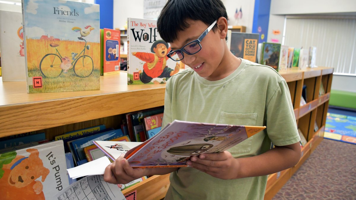 student reading a book in the media center
