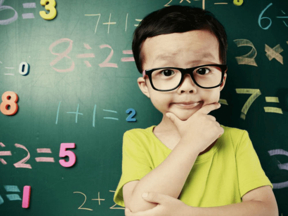 boy in glasses in front of math chalkboard