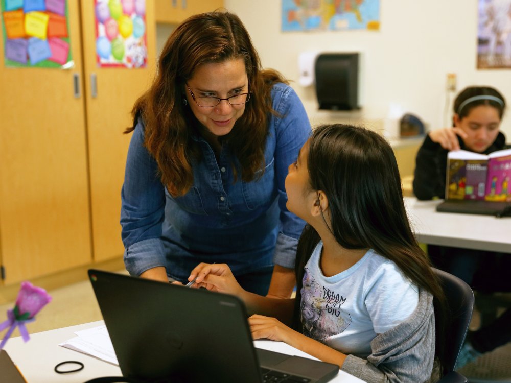 Teacher works with student at her laptop