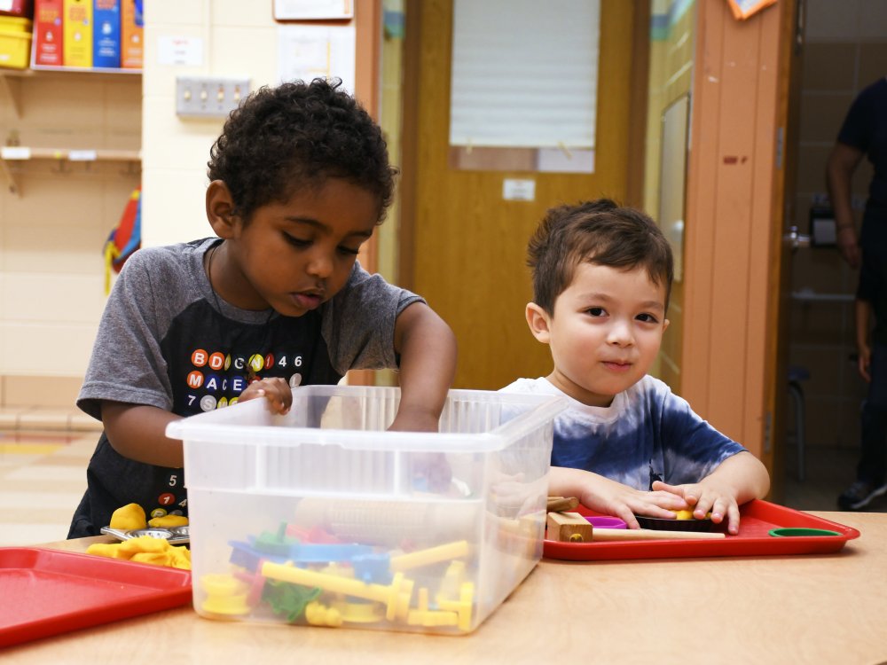 Two early learning students play with blocks at a table