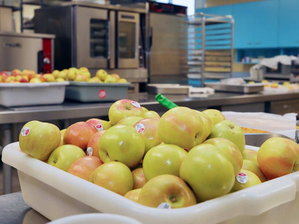 A bin of apples in a school cafeteria
