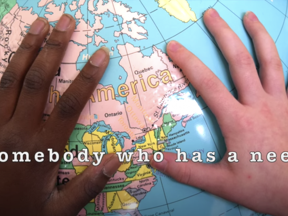 Two hands on a globe with the text "Somebody who has a need"