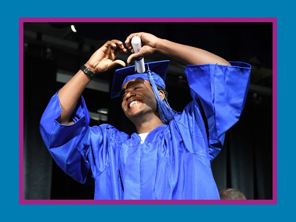 student in cap and gown making a heart with his hands