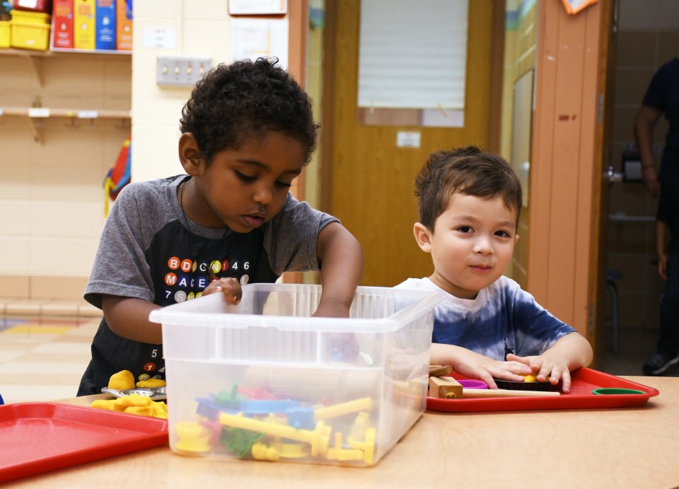 Two early learning students play with blocks at a table