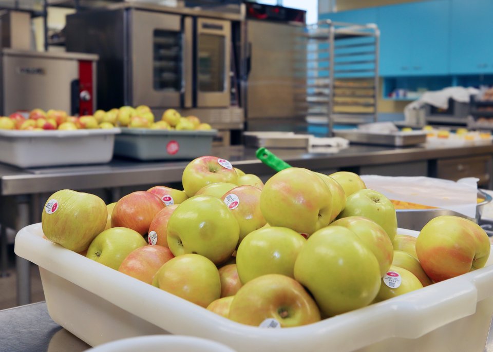 A bin of apples in a school cafeteria
