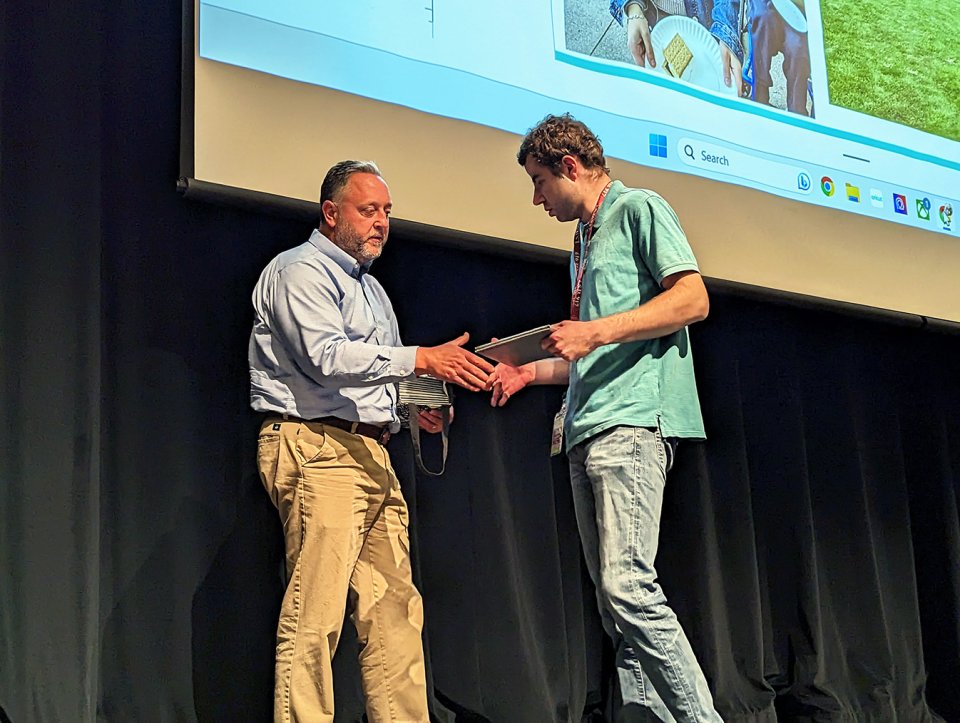 adult student in blue shirt and jeans receiving diploma
