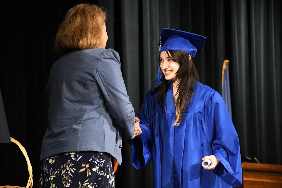student in cap and gown accepting diploma
