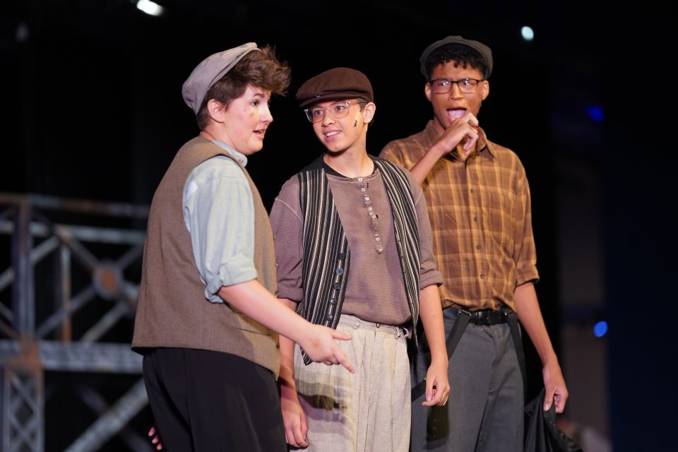 three actors performing the musical Newsies on stage